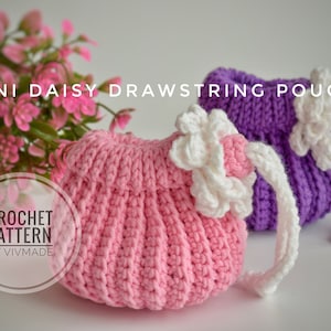 May include: Two crocheted drawstring pouches, one pink and one purple, with white crocheted flowers on top. The pouches are on a white surface. "CROCHET PATTERN BY VIVMADE" is written in a circle on the image.