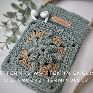 May include: A crocheted phone pouch with a floral design in shades of green and brown. The pouch has a strap and a leather tag that says "Homemade".