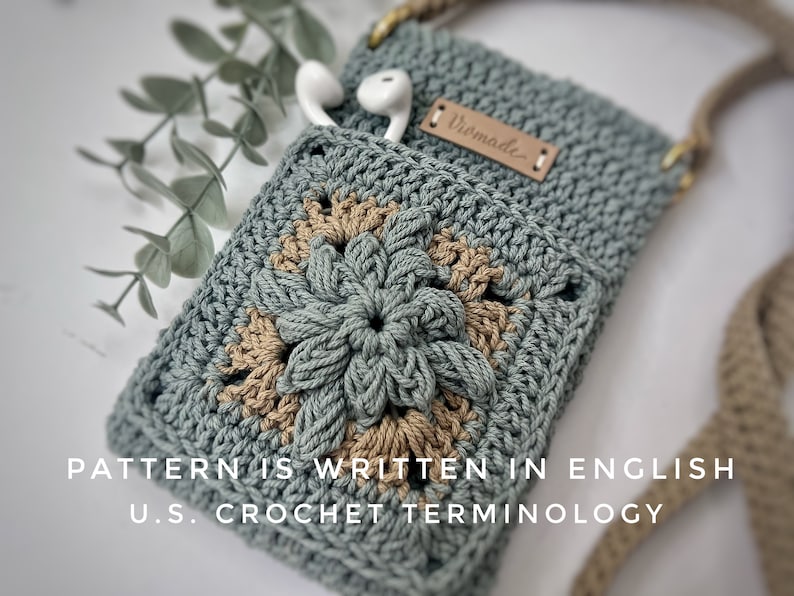 May include: A crocheted phone pouch with a floral design in shades of green and brown. The pouch has a strap and a leather tag that says "Homemade".