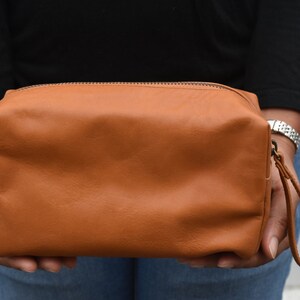 May include: A brown leather travel bag with a zipper closure and a carrying handle.