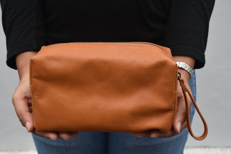 May include: A brown leather travel bag with a zipper closure and a carrying handle.