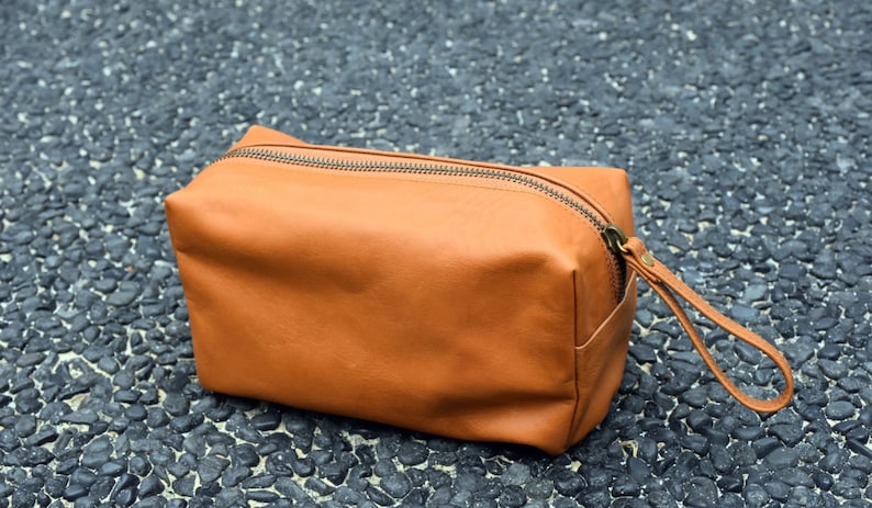 May include: A brown leather travel toiletry bag with a zipper closure and a leather strap.