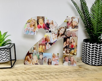 Könnte beinhalten: Eine weiße Acrylzahl 21 mit einer Collage aus Fotos von Menschen. Die Fotos sind in einem zufälligen Muster angeordnet und zeigen eine Vielzahl von Personen, darunter Paare, Familien und Freunde. Die Zahl steht auf einer Holzoberfläche.