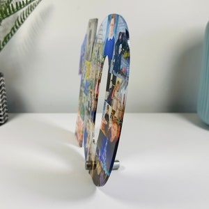May include: A clear acrylic number ten with a collage of photos printed on it. The number is standing on a white surface.