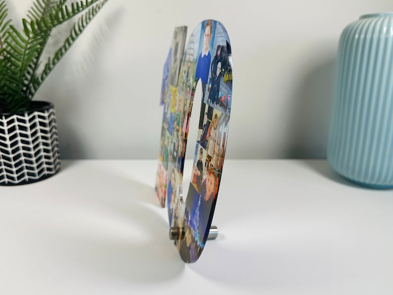 May include: A clear acrylic number ten with a collage of photos printed on it. The number is standing on a white surface.