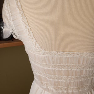 May include: White lace-trimmed slip dress with a scalloped neckline and a gathered skirt.