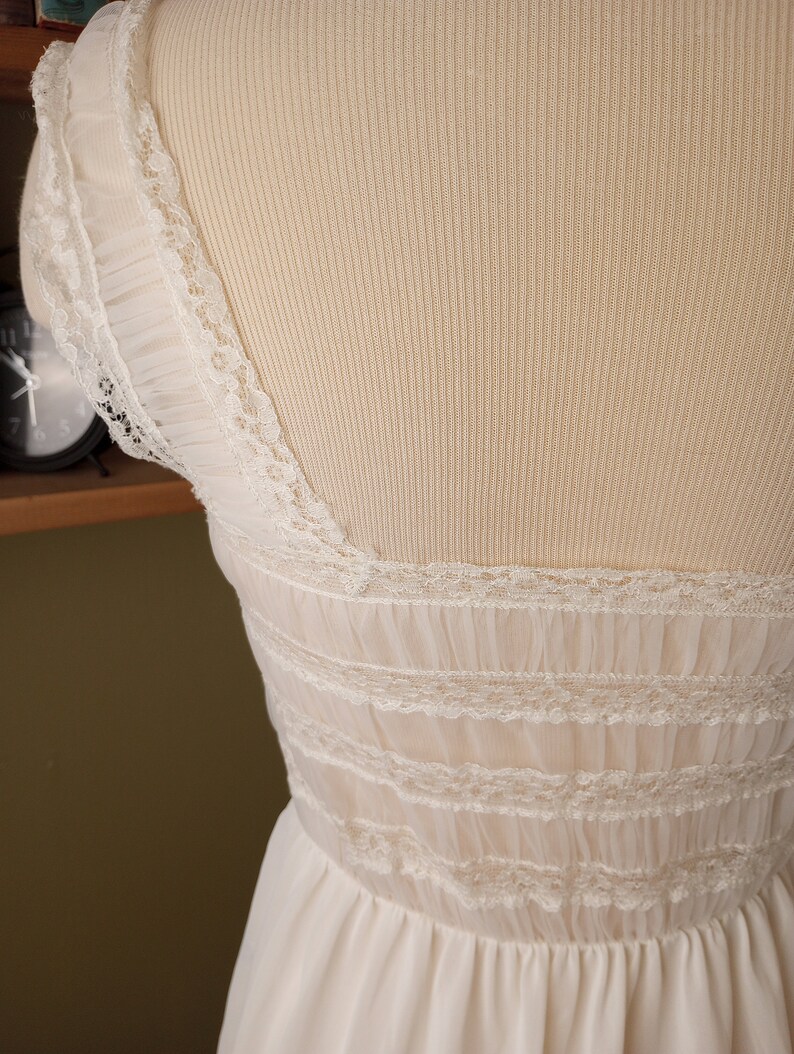 May include: White lace-trimmed slip dress with a scalloped neckline and a gathered skirt.