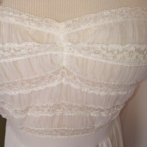 May include: A white lace and tulle dress with a sweetheart neckline. The dress has a fitted bodice and a flowing skirt.