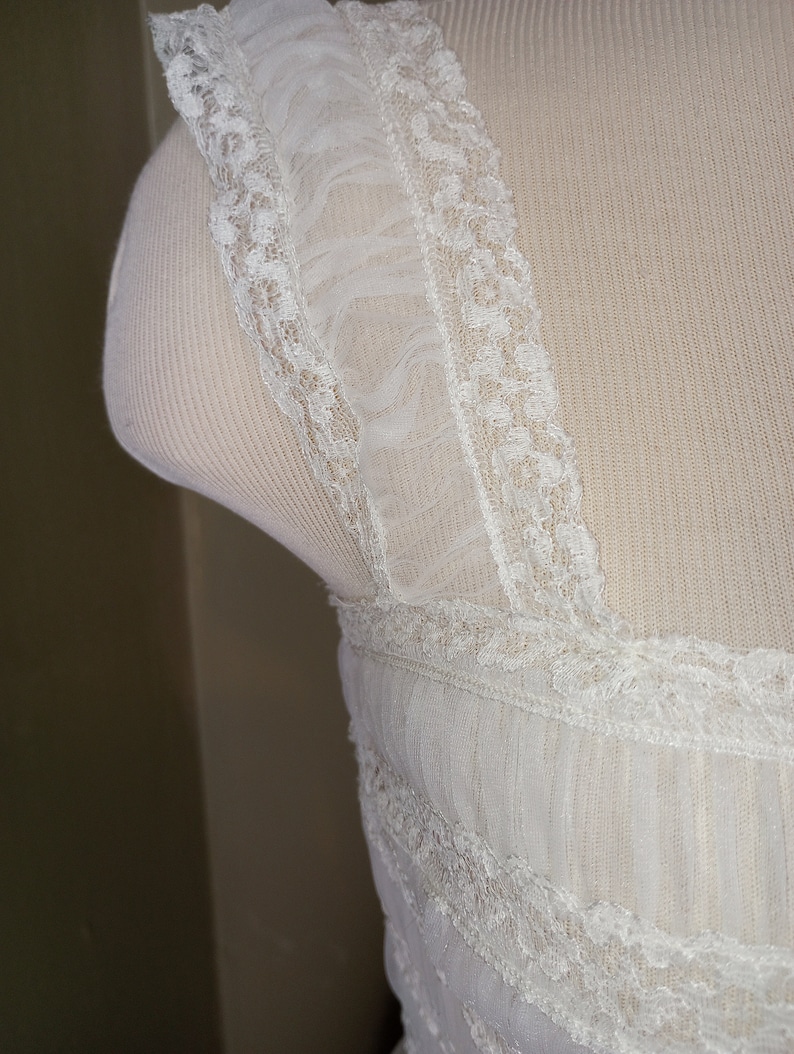 May include: White lace trim with a ruffled edge. The lace is delicate and intricate, with a floral pattern.