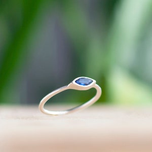 Peut inclure: Une bague en argent avec une pierre précieuse bleue en forme de marquise.