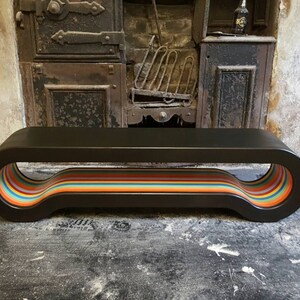 May include: A black wooden bench with a curved design and a rainbow stripe detail on the underside.