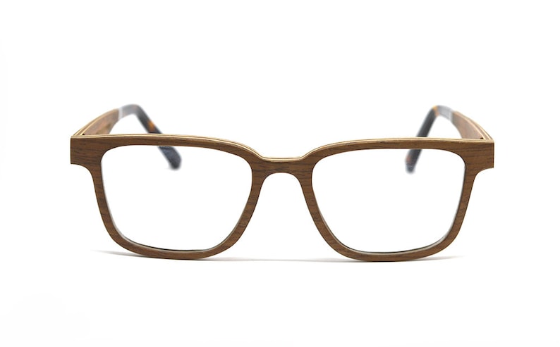 K&ouml;nnte beinhalten: Brille mit einem rechteckigen Rahmen in brauner Holzmaserung. Die B&uuml;gel sind d&uuml;nn und gerade und gehen an den Enden in ein dunkles Schildpattmuster &uuml;ber. Der Steg ist gerade und verbindet die beiden breiten &Ouml;ffnungen f&uuml;r die Gl&auml;ser.