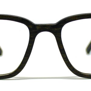 K&ouml;nnte beinhalten: Brille mit einem dunkelbraunen Rahmen in Holzmaserungsoptik. Der Rahmen hat eine rechteckige Form mit abgerundeten Ecken und einem Steg, der die beiden Gl&auml;ser verbindet. Die B&uuml;gel sind seitlich am vorderen Rahmenteil zu erkennen.