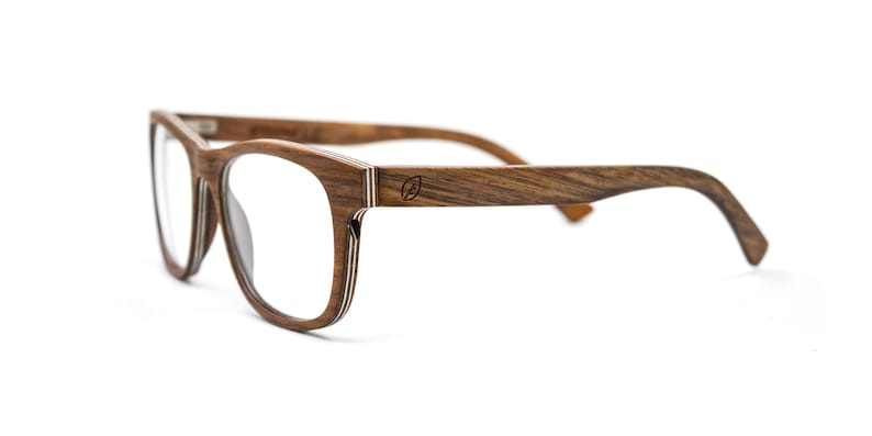 May include: Eyeglasses with a dark brown wood grain frame featuring a layered construction visible on the edges. The temples display a small circular logo with a leaf icon. The clear lenses are set within a rectangular frame shape.