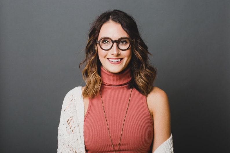 May include: Round tortoiseshell eyeglasses with a dark brown patterned frame. The eyewear features a classic circular shape and a polished finish, providing a distinct look. These glasses are designed with a sturdy bridge and thin, lightweight temples.