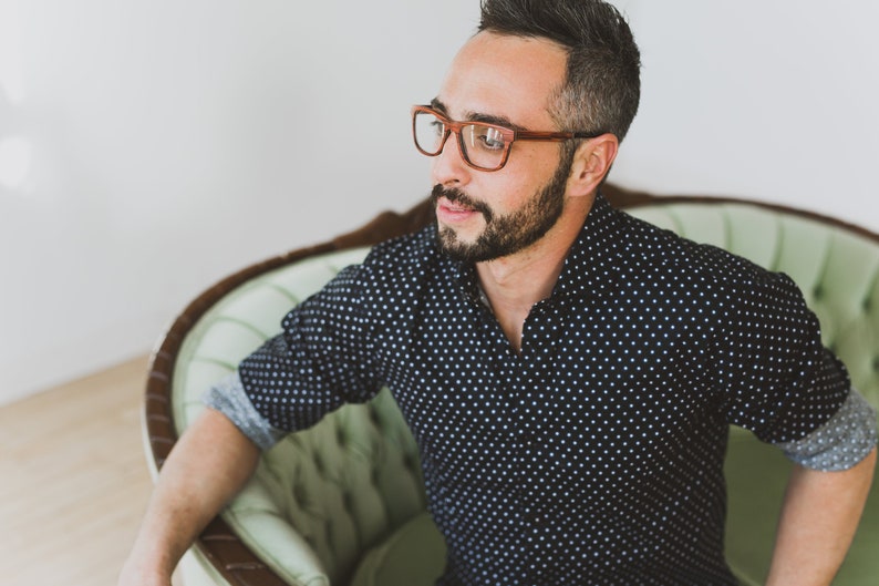 May include: A pair of brown-rimmed eyeglasses with a rectangular frame shape. The glasses feature a warm, wood-toned finish on the rims and temples, providing a distinct contrast against the face. The design is simple, functional, and classic.