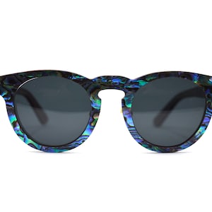 May include: Round sunglasses with a blue, green, and iridescent shell pattern on the frames. The lenses are dark gray.