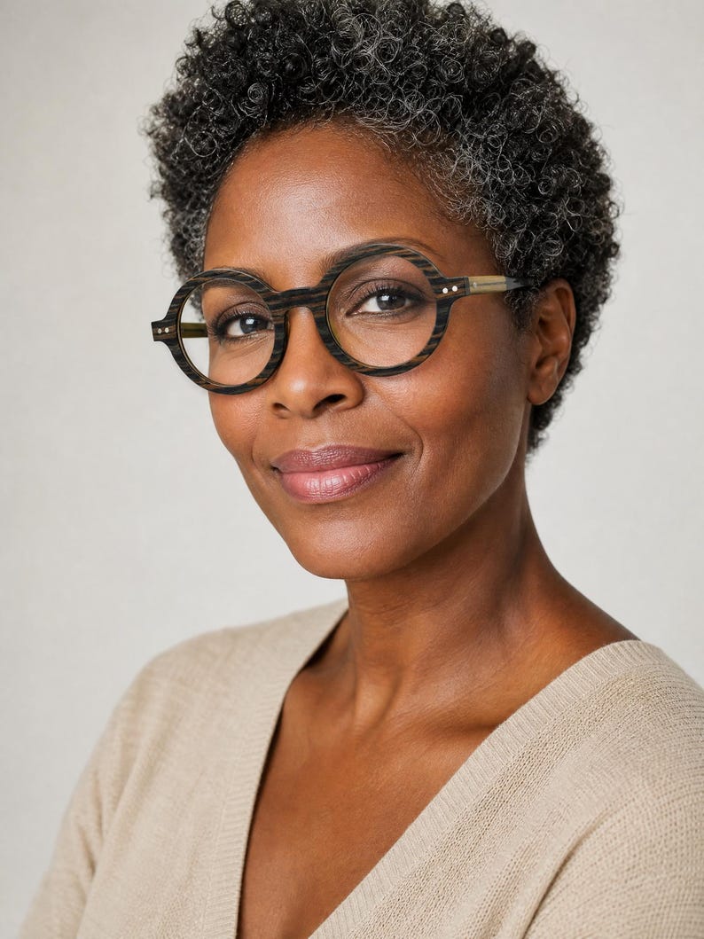 May include: Round eyeglasses featuring a dark brown wood-grain textured frame with a distinct horizontal striped pattern. The glasses have thin, light-colored temple arms and small metallic rivets on the front corners of the circular rims.