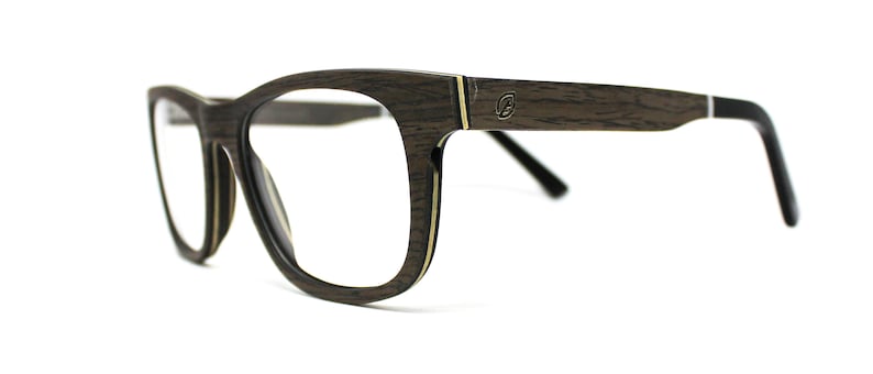 May include: Eyeglasses featuring a dark brown wood grain frame with a visible layered construction. The temples include a small metallic logo emblem near the hinge, a thin gold-tone accent line, and black plastic tips at the ends of the arms.