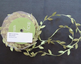 Puede incluir: Un carrete de cinta de vid de hoja verde oliva con una etiqueta que dice "4007-A Leaf Vine Olive Green $2.00 por yarda".