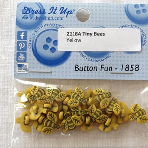 May include: A package of yellow tiny bee-shaped buttons with black details. The package includes a label that reads "2116A Tiny Bees Yellow" and "Button Fun - 1858". The buttons are made by Dress It Up.