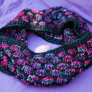 May include: A black, purple, and teal knitted infinity scarf with a textured pattern.