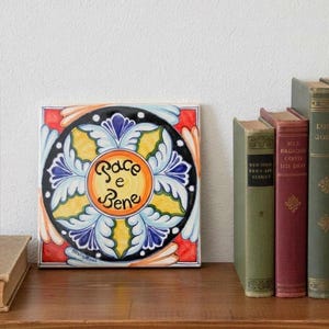 Może przedstawiać: Biały ceramiczny kubek z czarnym uchwytem i napisem "But First, Coffee" czarną, pogrubioną czcionką. Kubek stoi na drewnianej powierzchni.