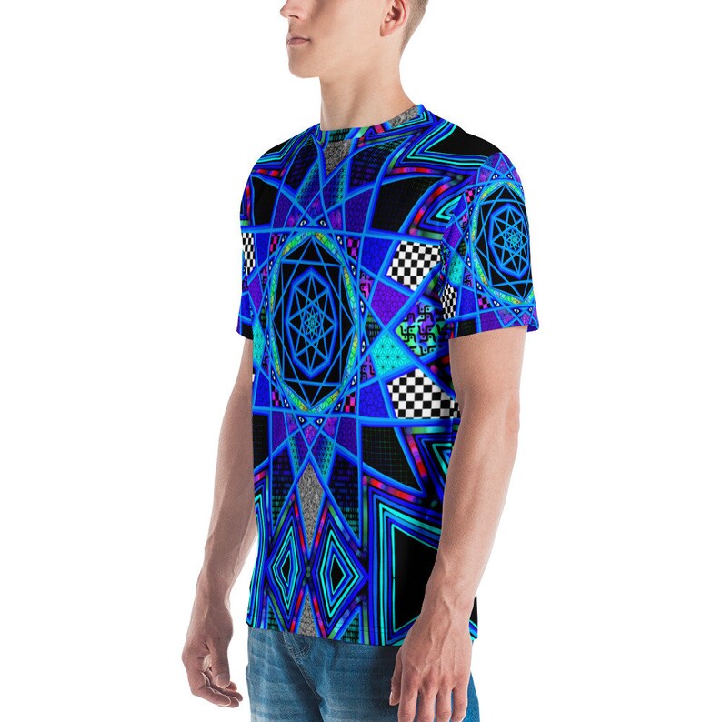 K&ouml;nnte beinhalten: Ein kurz&auml;rmeliges T-Shirt mit einem lebendigen geometrischen Design. Das Shirt zeigt ein komplexes Muster aus blauen, lila und schwarzen Formen, darunter Sterne, Diamanten und Schachbrettquadrate. Das Design ist auf wei&szlig;em Stoff gedruckt.