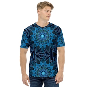 Peut inclure: Un t-shirt à manches courtes avec un motif géométrique bleu et noir. Le motif présente des formes d'étoiles et de losanges, créant un design symétrique. Le t-shirt est de style col rond.