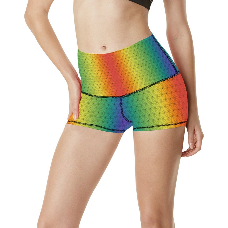 May include: Rainbow high-waisted athletic shorts with a geometric pattern. The shorts have a black waistband and a black trim around the leg openings.