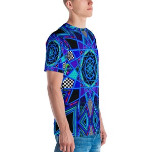 K&ouml;nnte beinhalten: Ein kurz&auml;rmeliges T-Shirt mit einem lebendigen geometrischen Design in Blau-, Schwarz- und T&uuml;rkist&ouml;nen. Das Muster umfasst sternartige Formen, Schachbrettquadrate und Rauten. Das T-Shirt wird getragen.