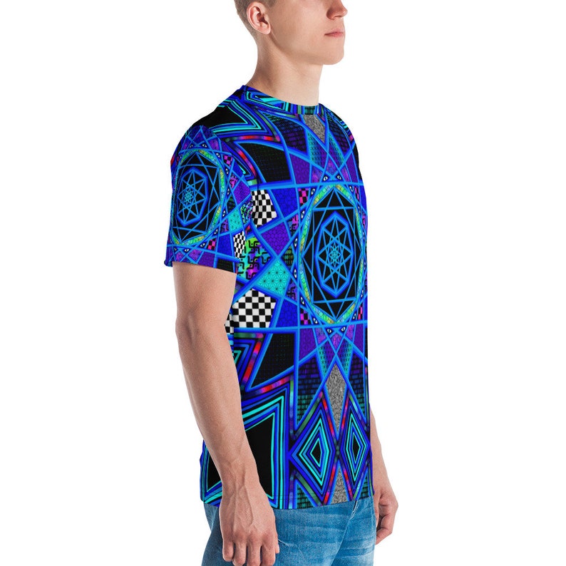 K&ouml;nnte beinhalten: Ein kurz&auml;rmeliges T-Shirt mit einem lebendigen geometrischen Design in Blau-, Schwarz- und T&uuml;rkist&ouml;nen. Das Muster umfasst sternartige Formen, Schachbrettquadrate und Rauten. Das T-Shirt wird getragen.