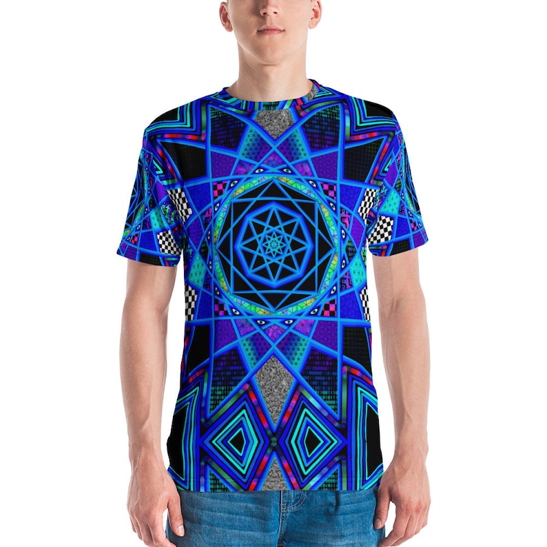 K&ouml;nnte beinhalten: Ein kurz&auml;rmeliges T-Shirt mit einem geometrischen Design in Blau, Schwarz und T&uuml;rkis. Das Muster umfasst sternartige Formen, Rautenmuster und karierte Akzente. Das Shirt ist aus einem weichen Material gefertigt.