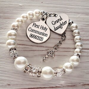 May include: White pearl bracelet with a silver charm that says "First Holy Communion 06/06/2020" and a heart-shaped charm that says "Granddaughter".