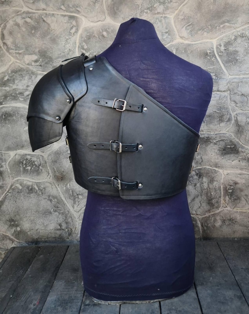 May include: Black leather armor with a metal shoulder piece. The armor has straps and buckles.