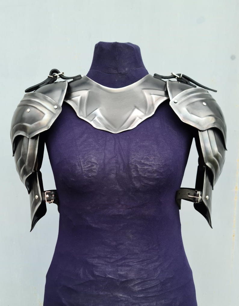 You can see blackened version of the pair of shoulders with gorget. The shoulders made from steel and protect your arm from neck to elbow. The shoulders have an ornament all over the entire surface of the metal.