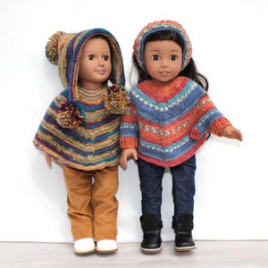 May include: Two dolls wearing hand-knitted ponchos. The left doll wears a hooded poncho with pom-poms and tan pants. The right doll wears a striped poncho with a matching beanie and dark blue jeans. Both dolls have dark hair and brown skin tones.