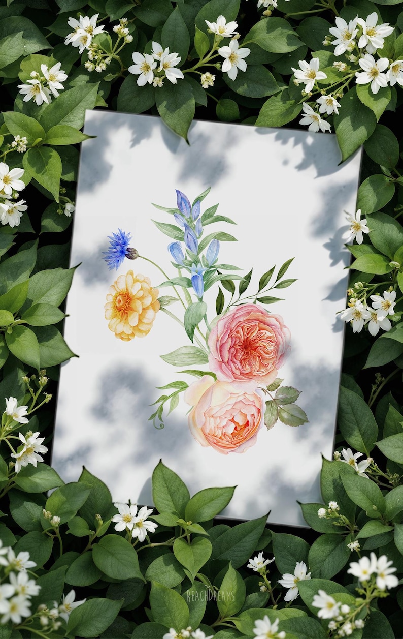 Op de afbeelding: Aquarel bloemenkunst print met een boeket rozen, blauwe klokjes en andere bloemen in roze, geel en blauw. Het kunstwerk staat tegen een witte achtergrond met een schaduweffect, omringd door groene bladeren en witte bloemen.