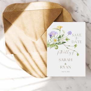 May include: Save the date card with a floral design featuring purple, white, and yellow flowers. The text reads "Save the Date for the wedding of Sarah & Ryan July 12, 2025".