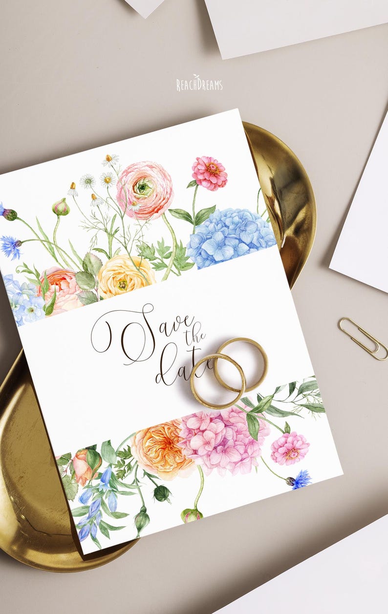 Op de afbeelding: Een witte huwelijksuitnodiging met bloemenranden en de tekst "Save the date". Het ontwerp toont roze, oranje, blauwe en gele bloemen, met twee gouden ringen.