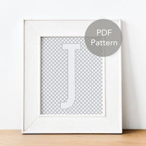 Könnte beinhalten: Ein weißer Rahmen mit einem schwarz-weißen Kreuzstichmuster des Buchstabens J. Der Rahmen hat einen weißen Passepartout und einen weißen Hintergrund. Ein grauer Kreis mit dem Text "PDF Pattern" befindet sich in der oberen rechten Ecke des Bildes.