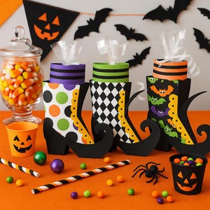 May include: Halloween-themed decorations featuring witch boot-shaped containers with various patterns, including polka dots, diamonds, and bats. Candy corn in a glass jar, jack-o'-lantern buckets, and decorative bats complete the festive scene on an orange surface.