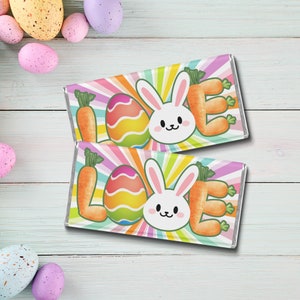 May include: Two colorful Easter-themed chocolate bar wrappers with a rainbow background, a bunny rabbit, and an Easter egg. The text on the wrappers says "Love".