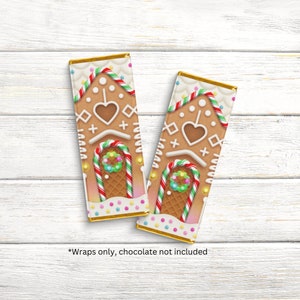 May include: Two rectangular gingerbread house wrappers with gold foil edges. The wrappers feature a brown gingerbread design with white icing details, candy cane accents, and a heart shape. The text "Wraps only, chocolate not included" is at the bottom.