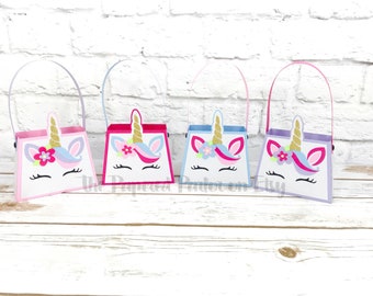 May include: Four unicorn-themed party favor bags with handles. The bags are pink, purple, blue, and white with gold glitter horns and pink flowers.