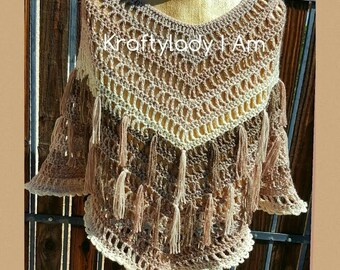 Könnte beinhalten: Ein gehäkeltes Poncho mit einem braunen und cremefarbenen Farbverlauf und Fransen. Das Poncho hat einen V-Ausschnitt und ist mit einem filigranen Stichmuster gearbeitet. Der Text "Kraftylady I Am" ist auf dem Poncho sichtbar.
