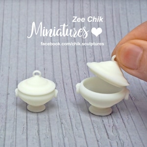 Puede incluir: Cuatro cuencos de servir de cerámica blanca con tapas, que van desde el tamaño pequeño hasta el grande. Los cuencos tienen un diseño clásico con un cuerpo redondeado y una tapa con un pomo en la parte superior. Los cuencos están dispuestos en una fila desde el más pequeño hasta el más grande, con el cuenco más grande con su tapa abierta.