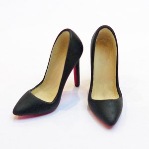 May include: A pair of black high-heeled shoes with red soles. The shoes are pointed-toe and have a classic pump style.