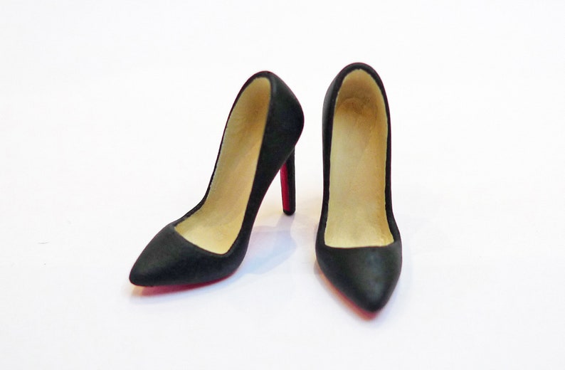May include: A pair of black high-heeled shoes with red soles. The shoes are pointed-toe and have a classic pump style.