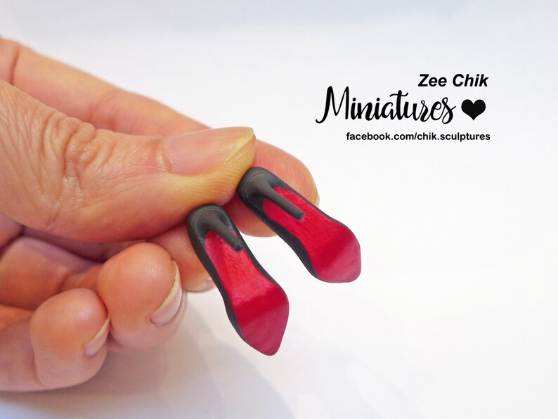 May include: A pair of miniature red high-heeled shoes with black heels. The shoes are made of polymer clay and are about the size of a fingernail. Zee Chik Miniatures facebook.com/chik.sculptures